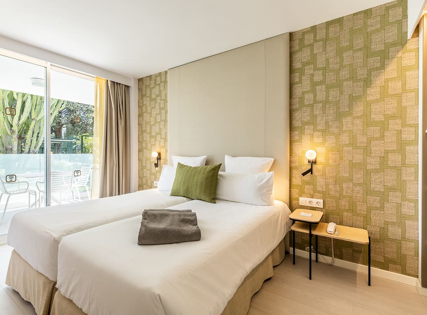 Twin bedroom in the apartment Apartment bedroom with two single beds, green wallpaper and access to a terrace overlooking the garden