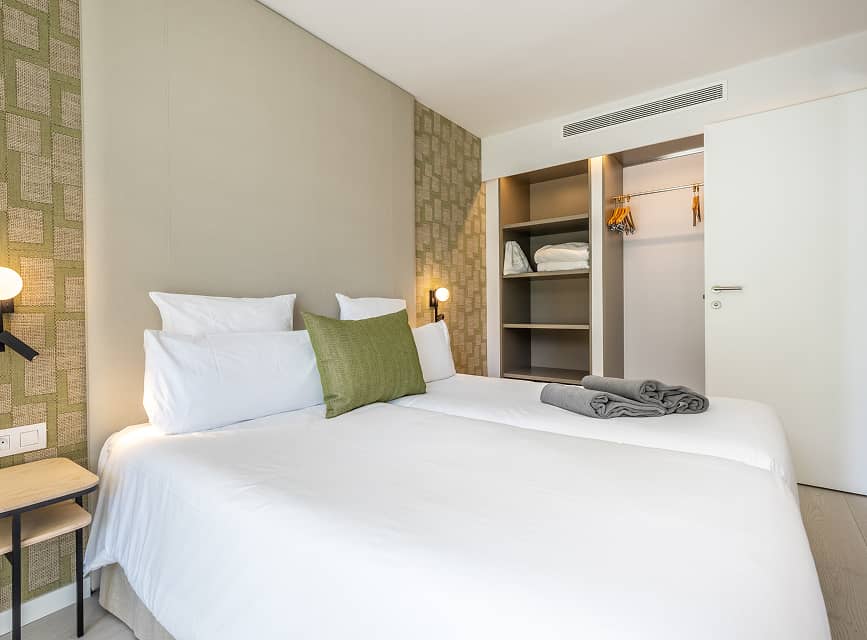 Apartment bedroom with wardrobe Single beds with white linen and an open wardrobe with shelves in the bedroom of a holiday apartment