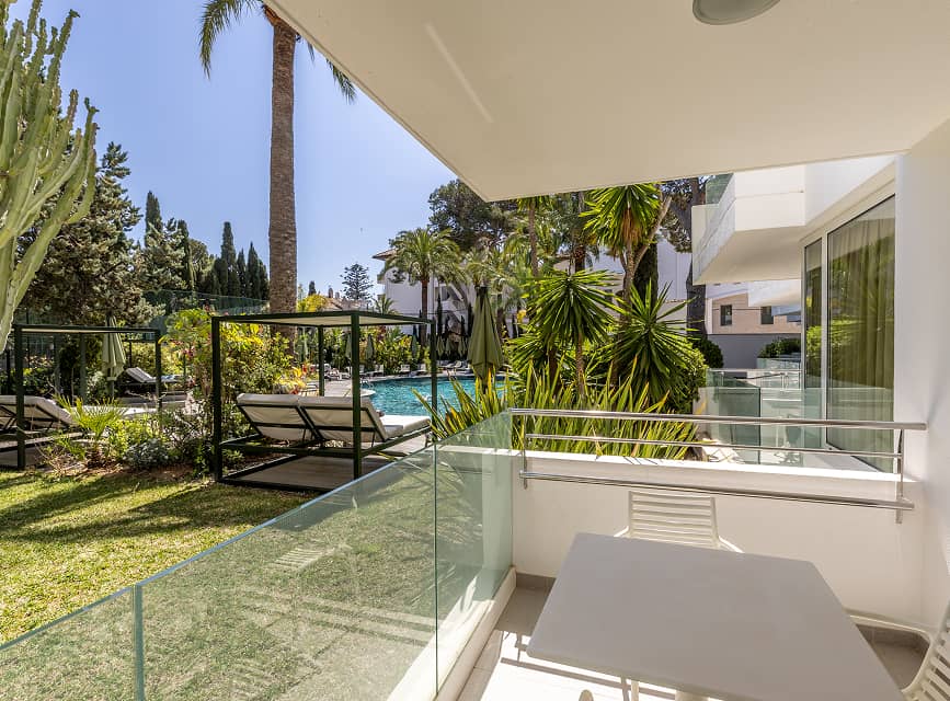 Apartment terrace with garden views Private terrace with glass balustrade overlooking the garden and pool at Illa d'Or Apartments