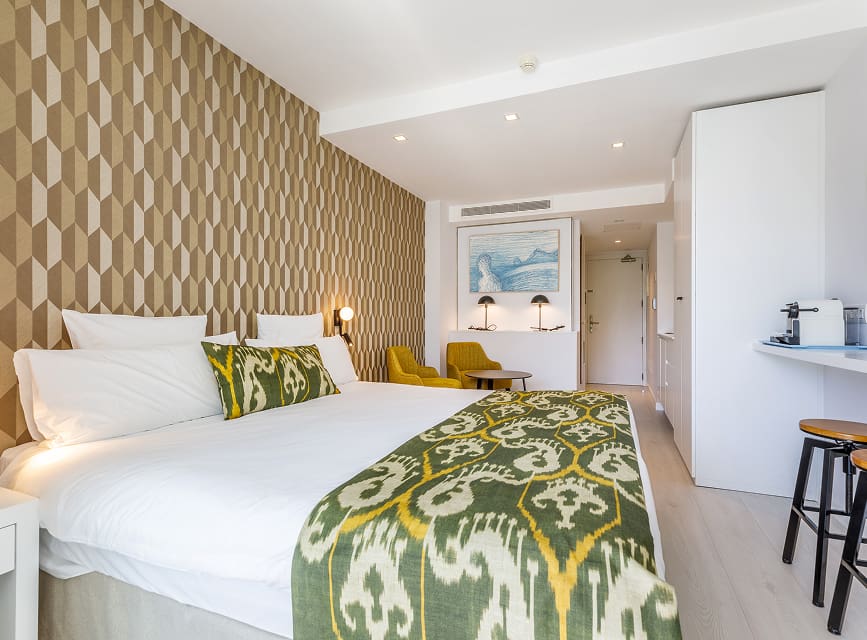 Studio at Illa d'Or Apartments Studio with double bed, geometric wallpaper, seating area and a counter with stools by the kitchen