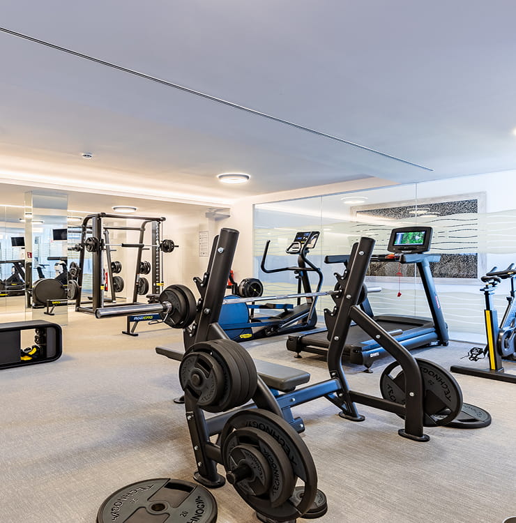 Fitnessraum mit Kraftgeräten, Hantelscheiben, Laufband und Spinning-Bike