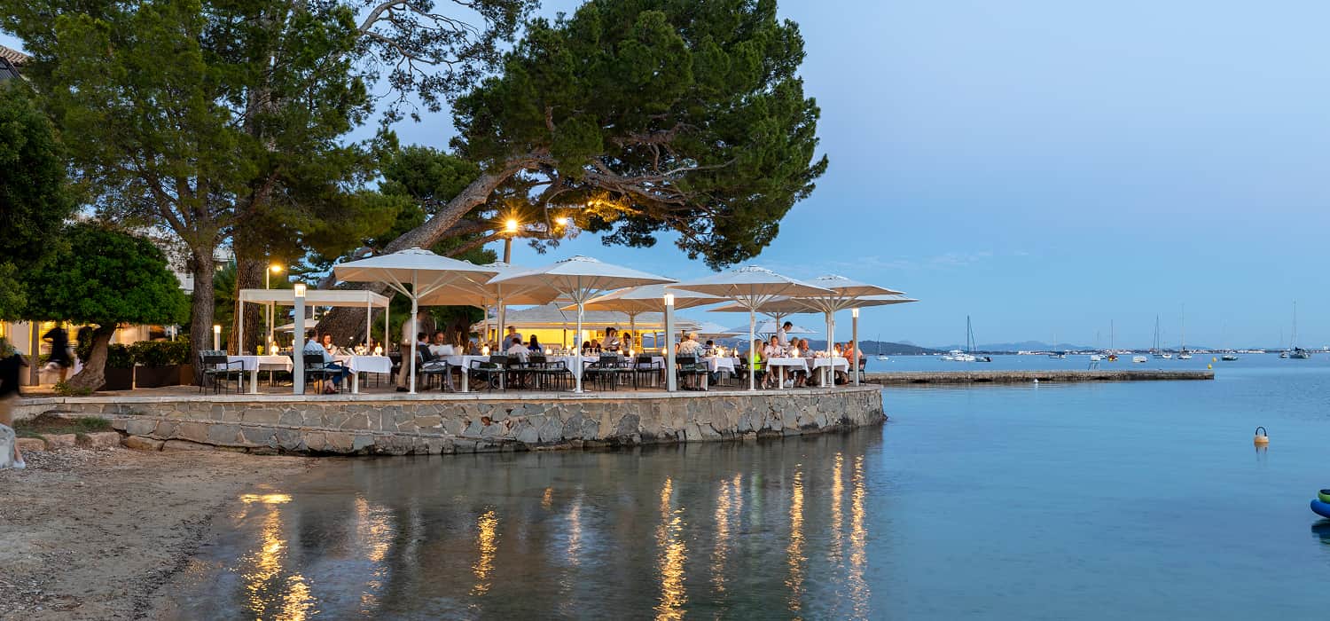 Beleuchtete Restaurantterrasse des Hotel Illa d'Or in der Abenddämmerung, bereit für Veranstaltungen in Puerto Pollensa