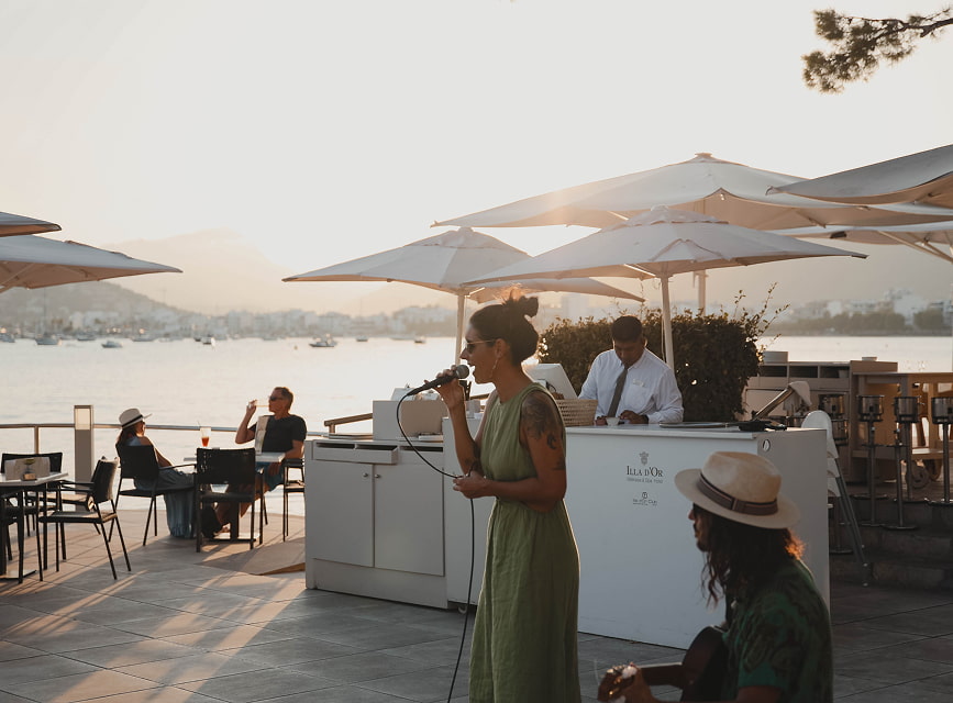 Sängerin und Gitarrist treten live auf der Terrasse am Meer bei einer Veranstaltung zum Sonnenuntergang auf