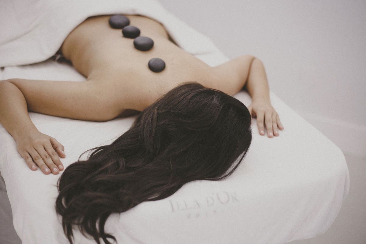 Frau bei einer Hot-Stone-Massage mit warmen Steinen auf dem Rücken im Spa