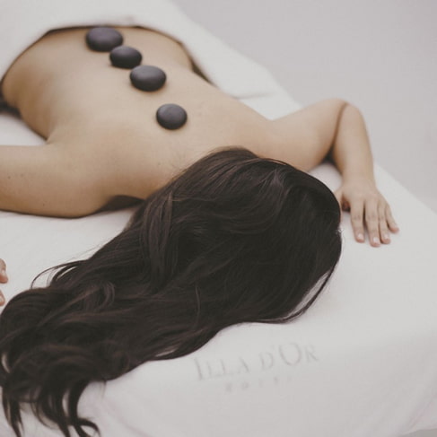Frau bei einer Hot-Stone-Massage mit warmen Steinen auf dem Rücken im Spa