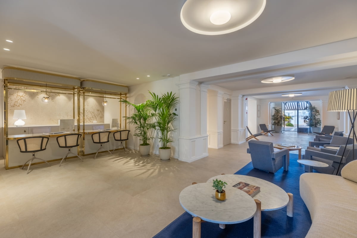 Großzügige Lobby mit Arbeitsbereich und Hockern, blauen Sesseln, Marmortischen und Pflanzen