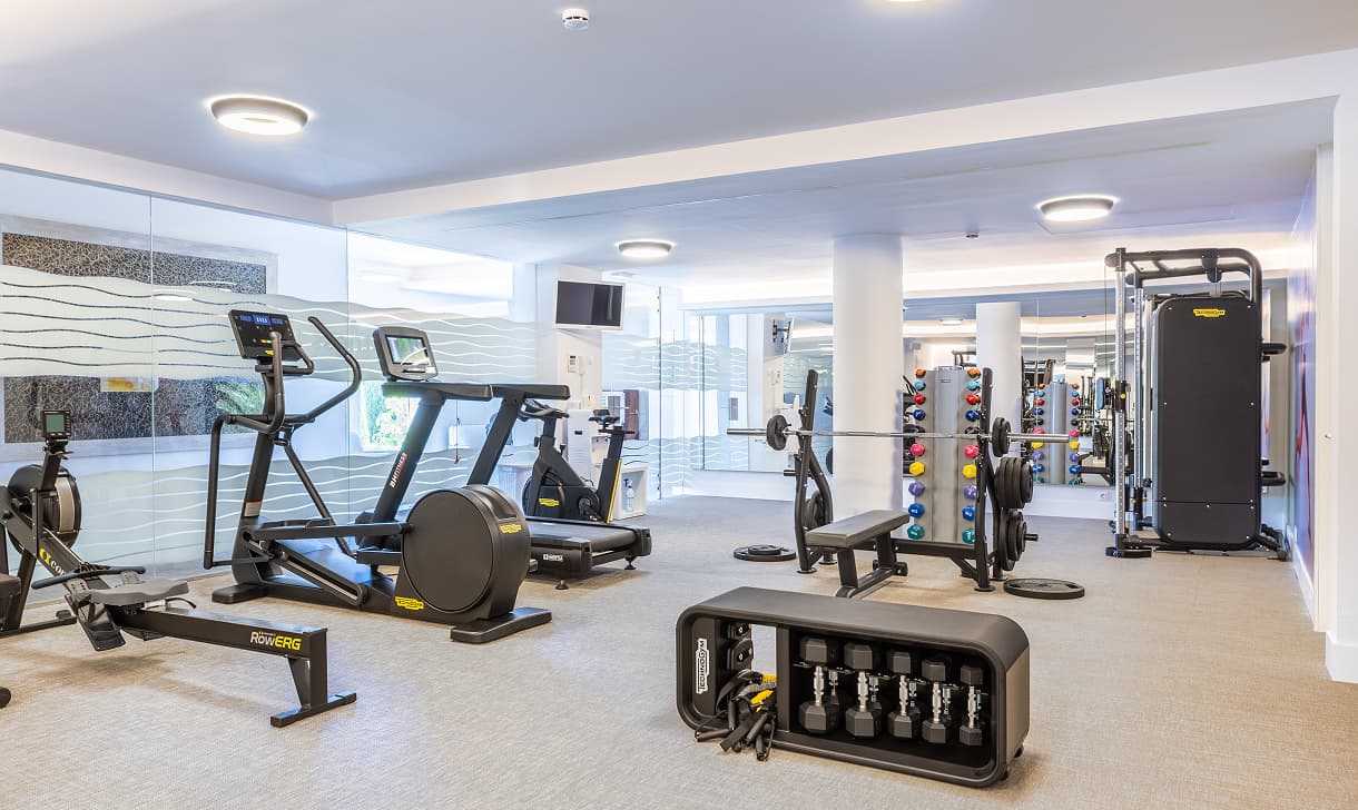 Moderner Fitnessraum mit Cardiogeräten, Rudergerät, Hanteln und Kraftstation