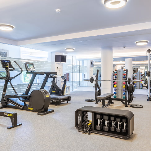 Moderner Fitnessraum mit Cardiogeräten, Rudergerät, Hanteln und Kraftstation