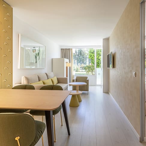 Heller Wohnraum mit Esstisch, Sofa und Sitzbereich, rechts das angrenzende Schlafzimmer