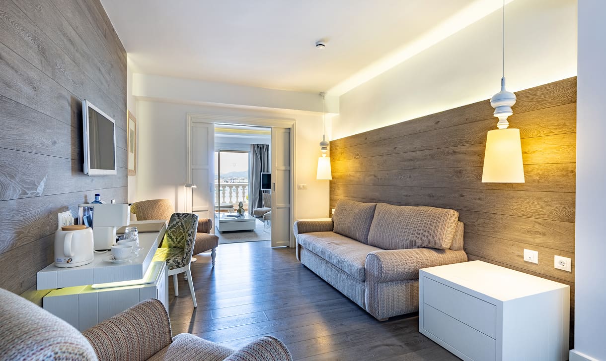 Wohnbereich mit Sofa, holzverkleideter Wand, Minibar und Kaffeemaschine, im Hintergrund der Blick nach draußen