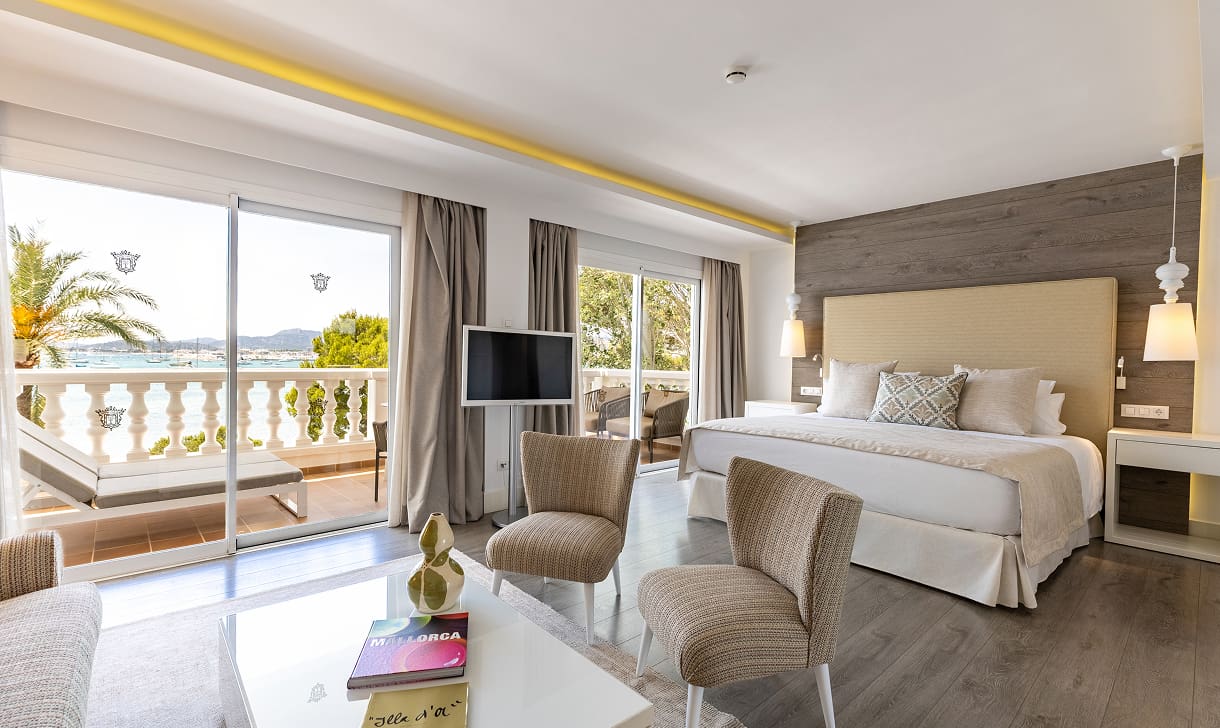 Geräumiges Zimmer mit Doppelbett, Sitzecke und großen Fenstern zur Terrasse mit Blick auf die Bucht