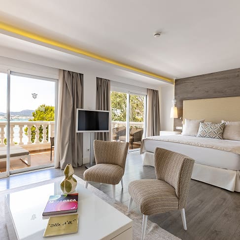 Geräumiges Zimmer mit Doppelbett, Sitzecke und großen Fenstern zur Terrasse mit Blick auf die Bucht