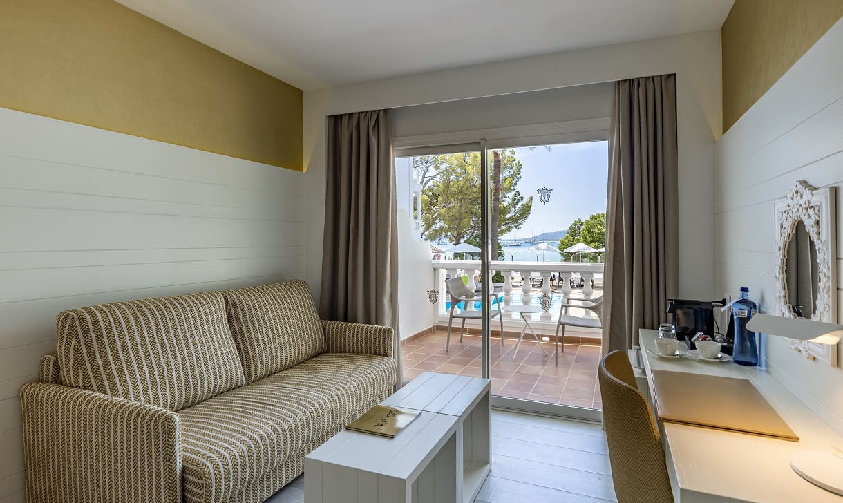 Sitzbereich mit gepolstertem Sofa, Couchtisch, Schreibtisch und Glastür zur Terrasse