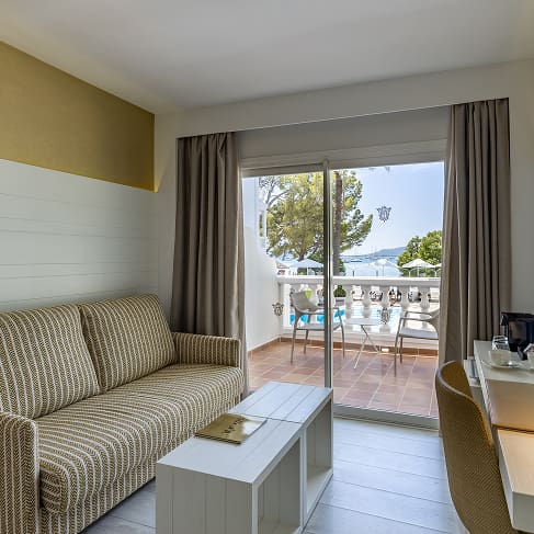 Sitzbereich mit gepolstertem Sofa, Couchtisch, Schreibtisch und Glastür zur Terrasse
