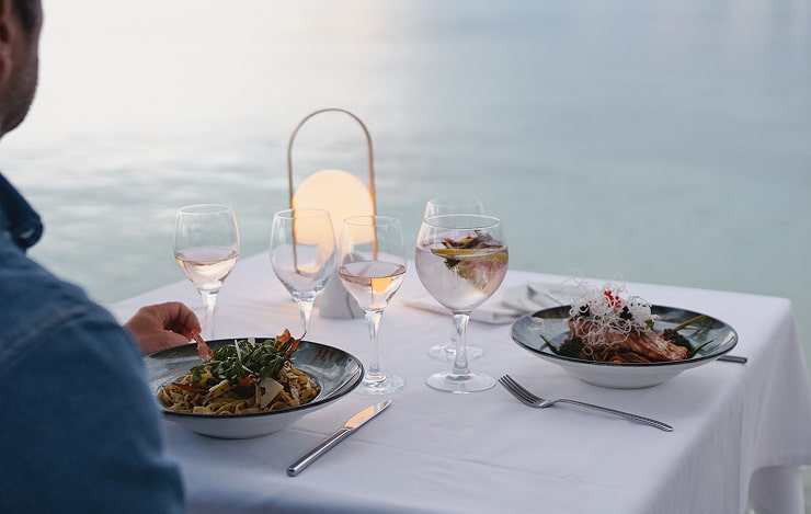 Seaside dinner in Puerto Pollensa Dinner for two with pasta dishes, wine glasses and a lantern at a seafront restaurant in Puerto Pollensa