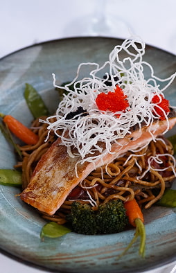Signature cuisine at Hotel Illa d'Or Salmon fillet on stir-fried noodles with vegetables and a crispy topping, one of the restaurant's dishes