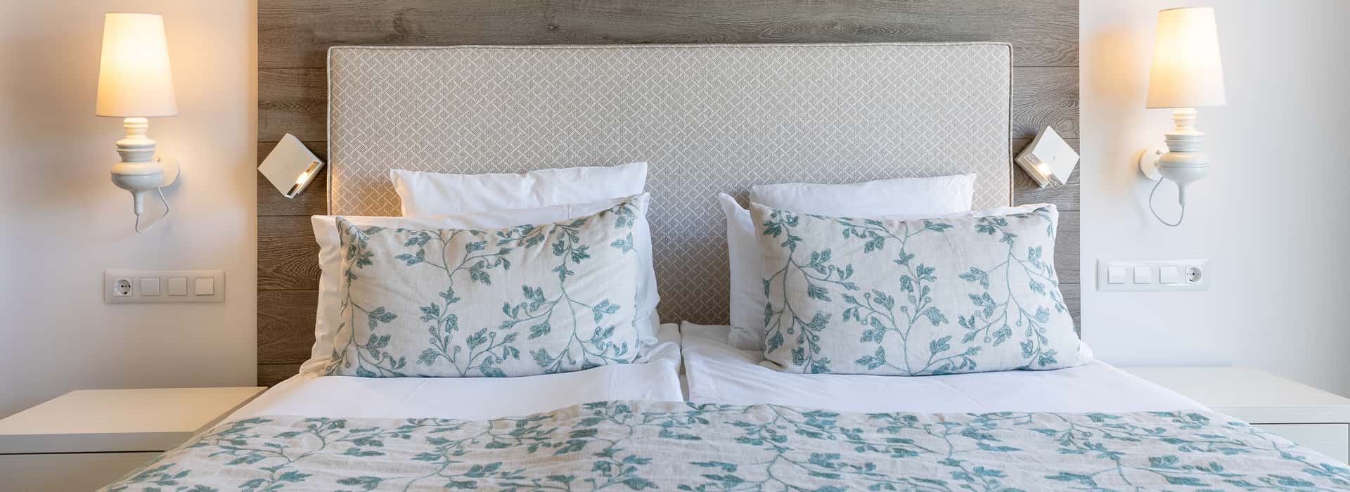Hotel Illa d'Or | Standard Room Detail of the headboard, with bed linen featuring sea-blue flowers