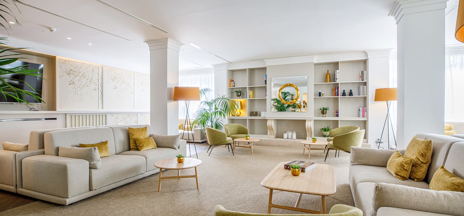 Salón amplio con sofás, butacas, mesas bajas, lámparas de pie y estanterías decorativas