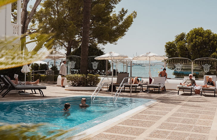 Piscina frontal Adults Only del hotel con tumbonas, sombrillas y vistas al mar Mediterráneo