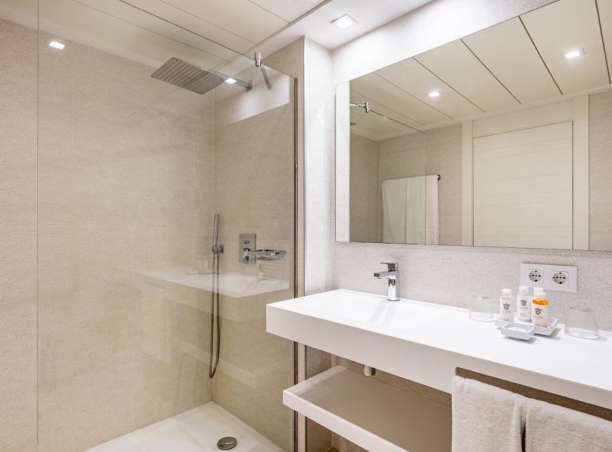 Bathroom with rain shower, wall-hung washbasin, large mirror and toiletries