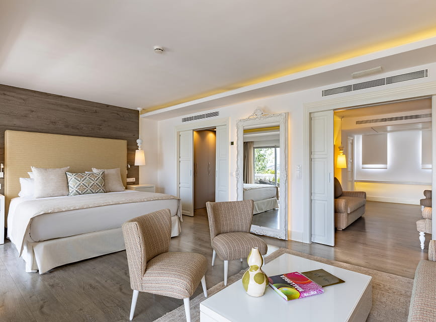 Suite with a double bedroom, armchairs and a sliding door leading to the living room with sofa
