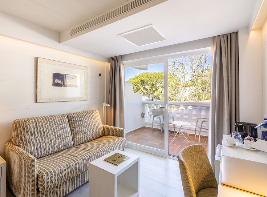 Seating area with sofa, side table and glass door onto the balcony overlooking the pines