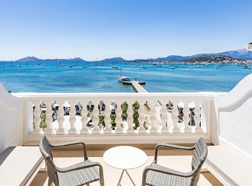 Balcony with two chairs and a table facing Pollensa Bay, overlooking the jetty and the mountains