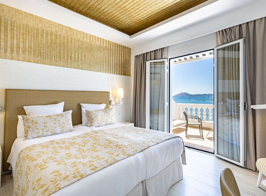 Room with two single beds and doors opening onto a balcony with views of the Mediterranean Sea